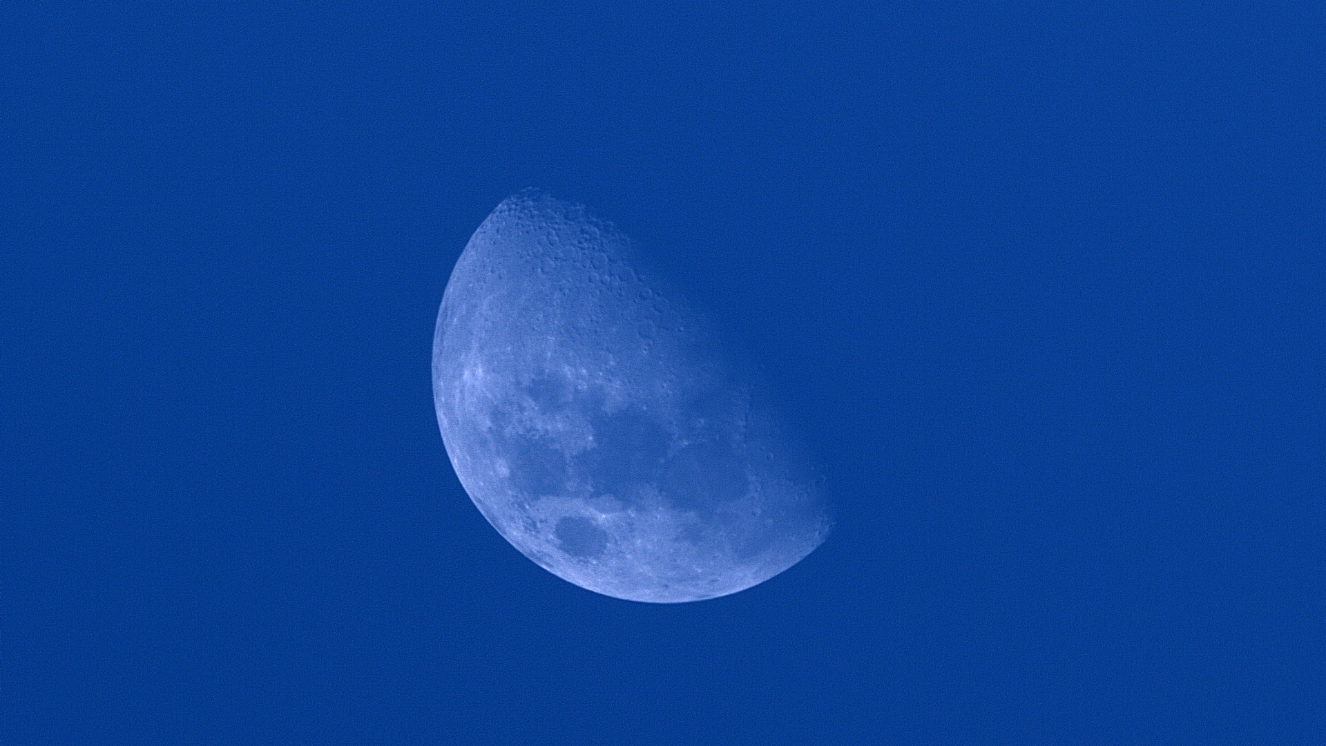 The Moon against a blue daytime sky